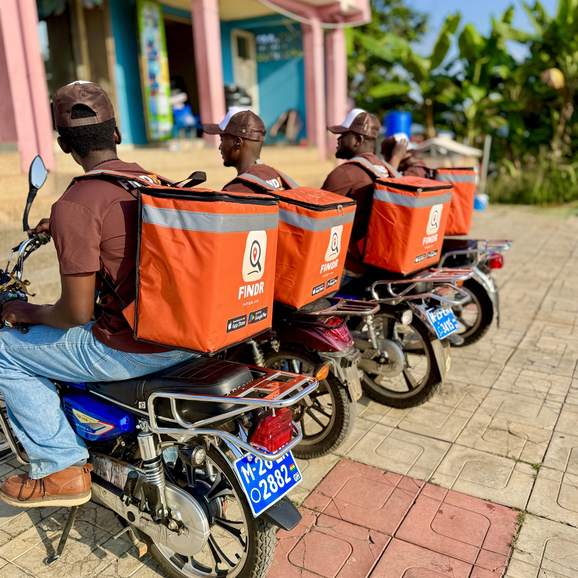 FINDR riders from behind with a row of orange delivery boxes