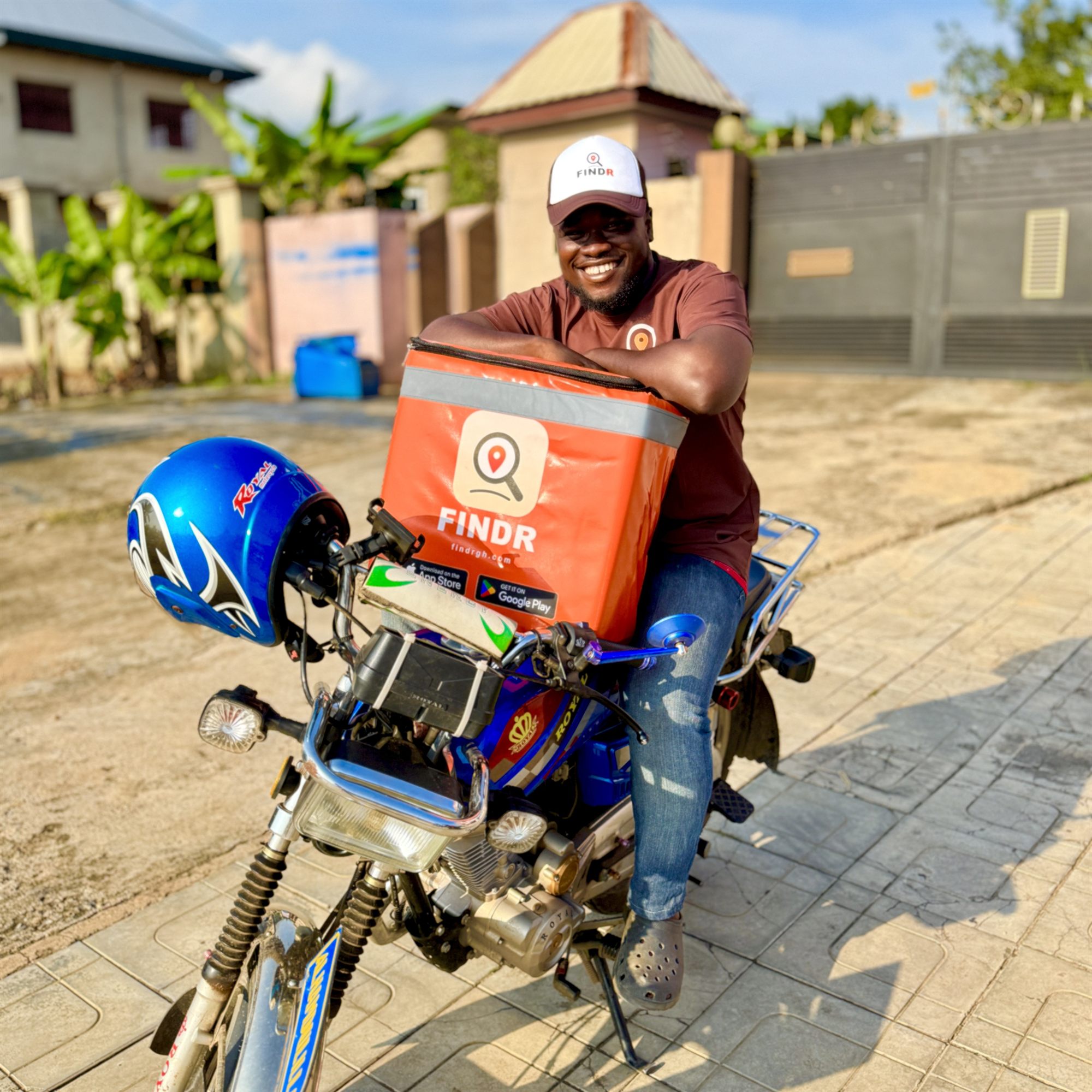 A smiling FINDR rider leaning on his orange delivery box