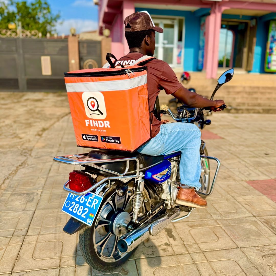 A FINDR rider riding away with an orange delivery box